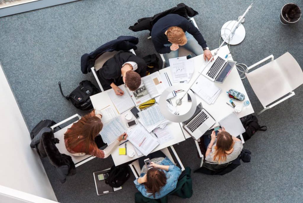 Group of office employees working together inside a coworking office meeting room.