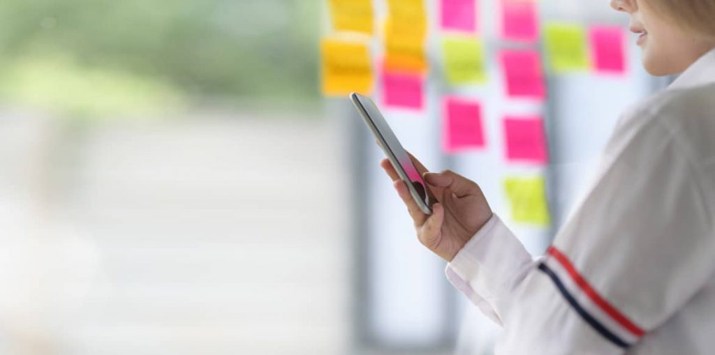 Collaboration will continue post COVID. An office worker using a coworking window with post it notes. 