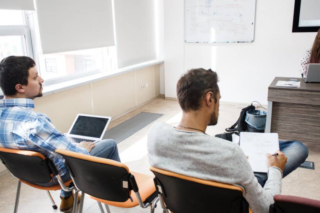 People at business seminar are listening the speaker's presentation in office and making notes in a meeting room